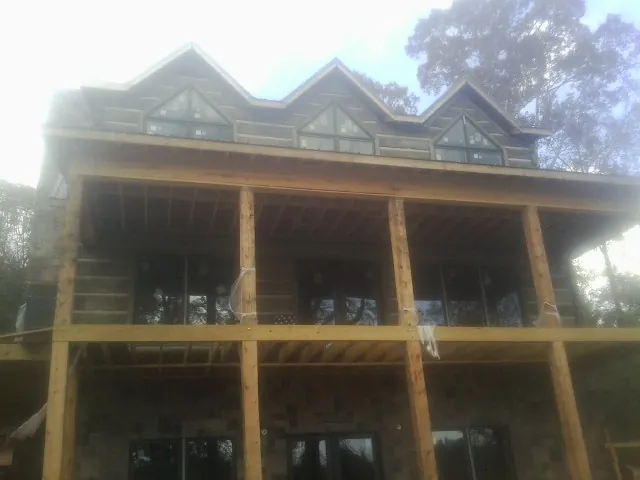 Dormers and porch framing on a large log home under construction — Roof Coating work by our crew in Elliston
