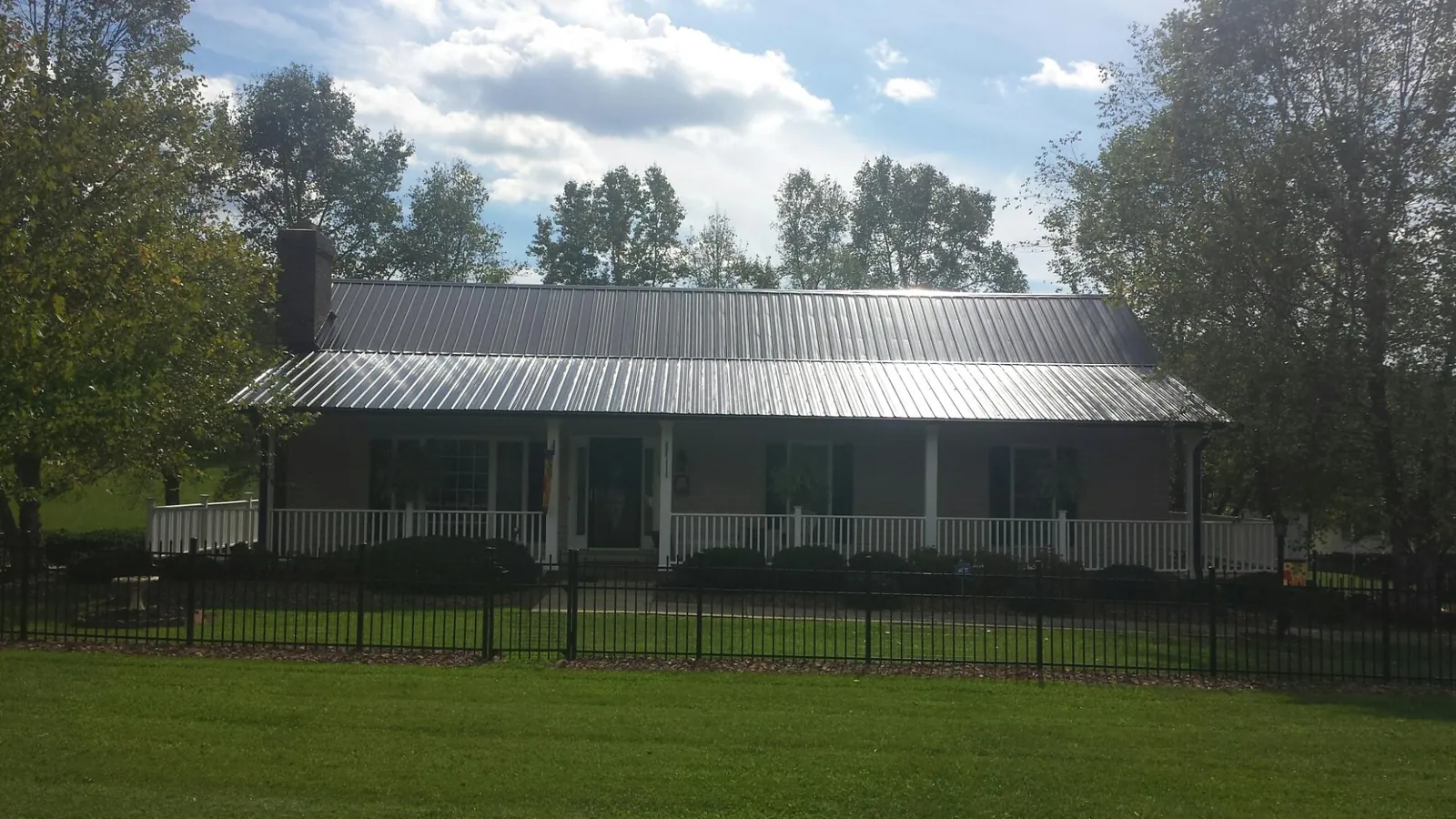 Gray metal roof on a brick ranch with a full width front porch — Gutter Guard Installation work by our crew in Elliston
