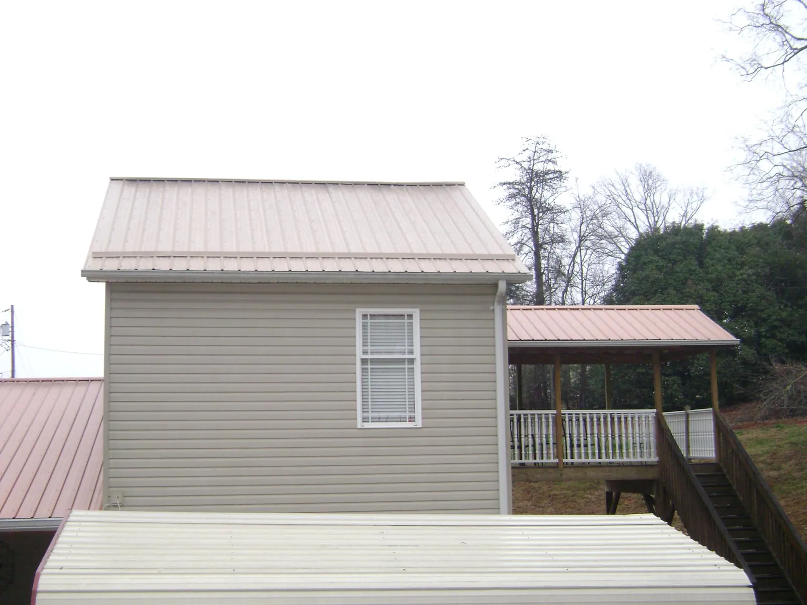 Tan metal roofs on a two story addition and attached porch, from a Roof Replacement job in Elliston